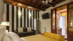 Une chambre d’hôtel avec un grand lit, un canapé, un téléviseur fixé au mur et un plafond en bois.