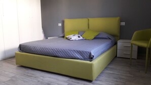 Une chambre à coucher moderne avec un lit vert, une table de chevet et une chaise verte.