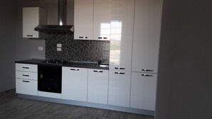 Une cuisine moderne avec des meubles blancs, un lave-vaisselle noir et un pare-feu en carrelage.