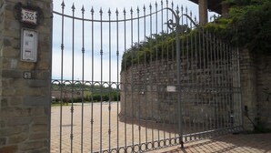 Un portail en fer forgé, un mur en pierre et un chemin pavé de briques menant à un bâtiment.