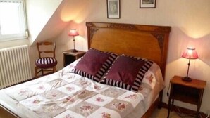 A bedroom with a wooden bed frame, floral bedding, two bedside lamps, a chair, and a radiator.