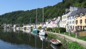 A calm waterfront with boats docked along the shore, surrounded by colorful buildings and lush greenery.