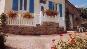 A house with a stone foundation, white fence, and blue shutters.