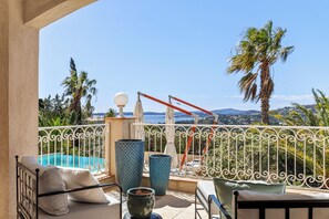 Un balcon avec piscine, des meubles d’extérieur et une vue sur la mer.