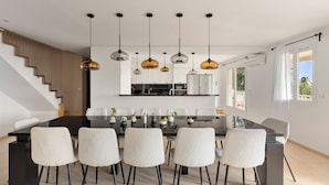 A modern kitchen with a central island, white cabinetry, and pendant lighting. - Villa 55 -Heated pool with exceptional view (Roquebrune-Sur-Argens)