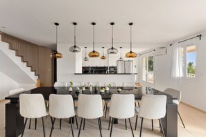 Une cuisine moderne dotée d’un îlot central, de meubles blancs et d’un éclairage suspendu.