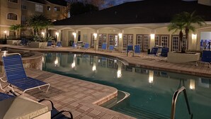 A swimming pool area with lounge chairs and a building with arched doorways. - Avalon Ground floor condo (clearwater)