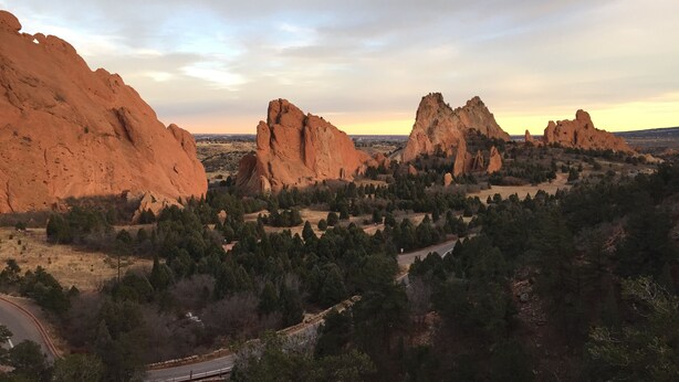 A landscape with prominent red rock formations and a road winding through a forested area. - Charming Family & Corporate Retreat Near Broadmoor (Colorado Springs)