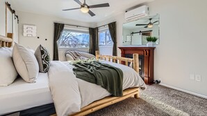 A bedroom with a bed, a ceiling fan, a window, and a mirror. - Charming Family & Corporate Retreat Near Broadmoor (Colorado Springs)