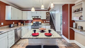 A modern kitchen with granite countertops, white cabinets, and a central island with red plates. - Charming Family & Corporate Retreat Near Broadmoor (Colorado Springs)