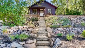 A house with a stone staircase leading to a front door, surrounded by a garden with various plants and a wooden fence. - Charming Family & Corporate Retreat Near Broadmoor (Colorado Springs)