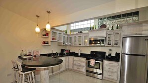 Una cocina moderna con armarios blancos, electrodomésticos de acero inoxidable y una isla central con taburetes de bar.