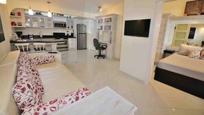 Un apartamento moderno con cocina, comedor y sala de estar con sofá y televisor.