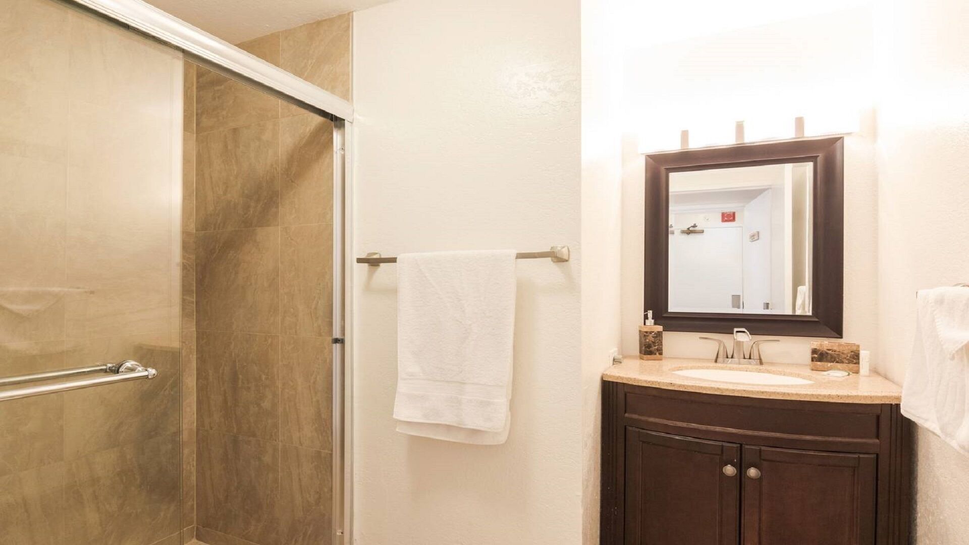 A bathroom with a shower, a sink, a mirror, and a towel rack.