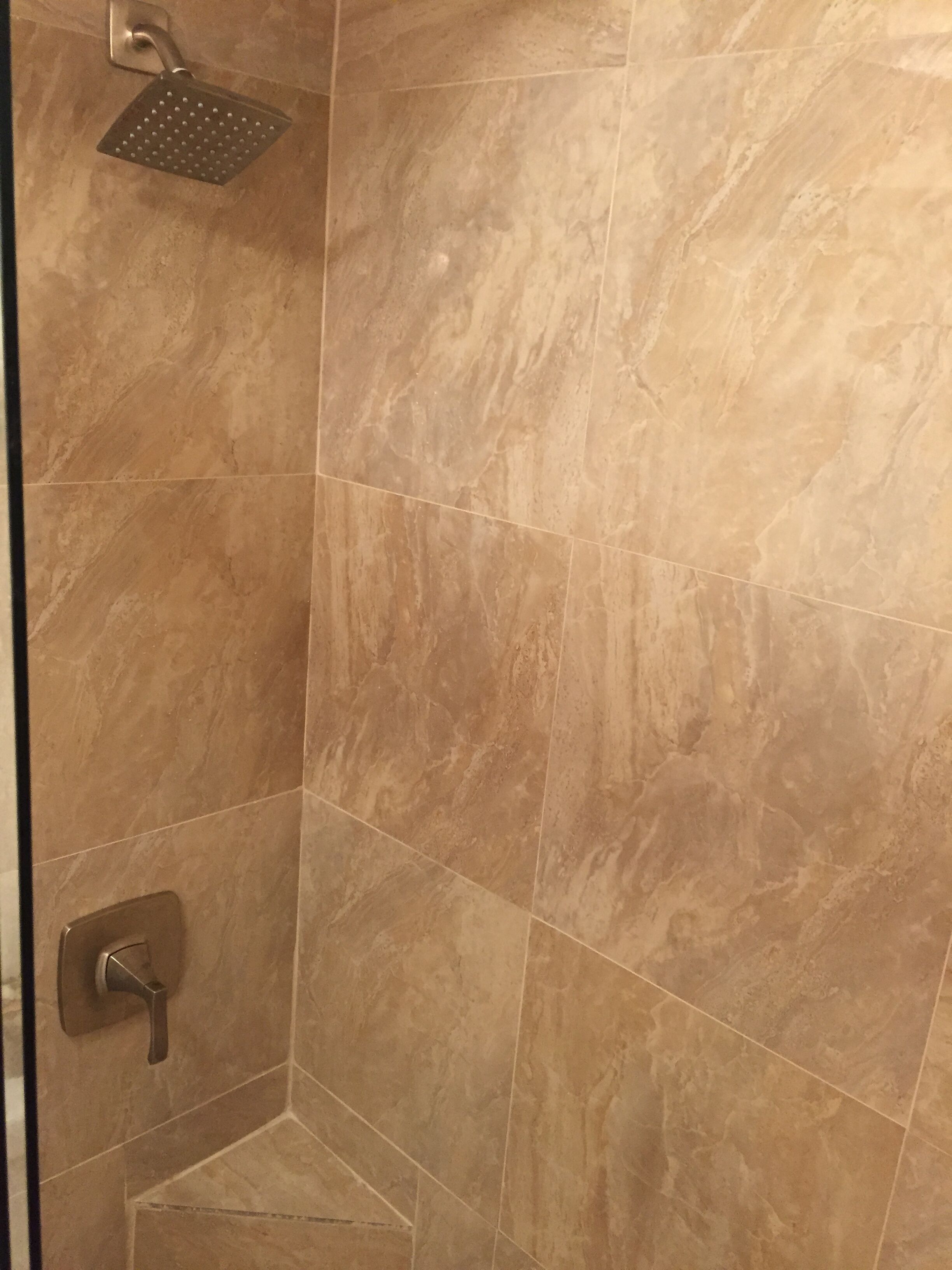 A shower area with a handheld showerhead and a wall-mounted control.