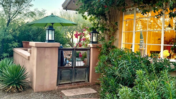 Una entrada de jardín con una puerta, un paraguas verde y una farola.