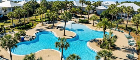 Un complexe hôtelier doté d’une grande piscine, de palmiers et de chaises de plage.
