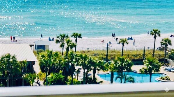 A beach view with palm trees, a swimming pool, and a building with a sloped roof. - ☀️SUMMER ISN’T OVER! Escape to Sterling Shores in Destin 🌊🏖️ make one more memory! (Destin)