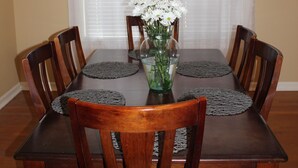 Una mesa de comedor con seis sillas de madera, un jarrón con flores y una araña.