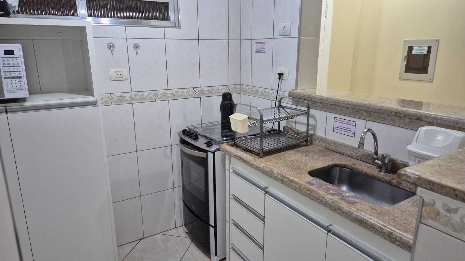A compact kitchen with a built-in oven, a sink, and a microwave.