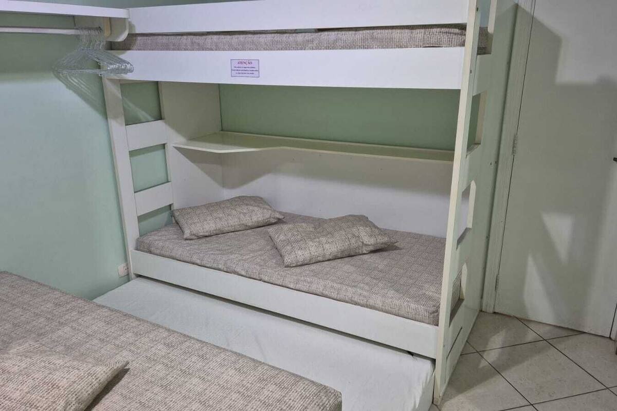 Een slaapkamer met een stapelbed, een onderbed en een uitschuifbaar bureau.