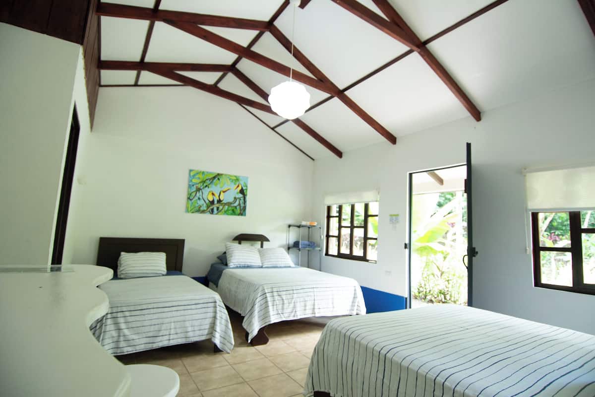 A room with two beds, a painting on the wall, and a door leading to a balcony.