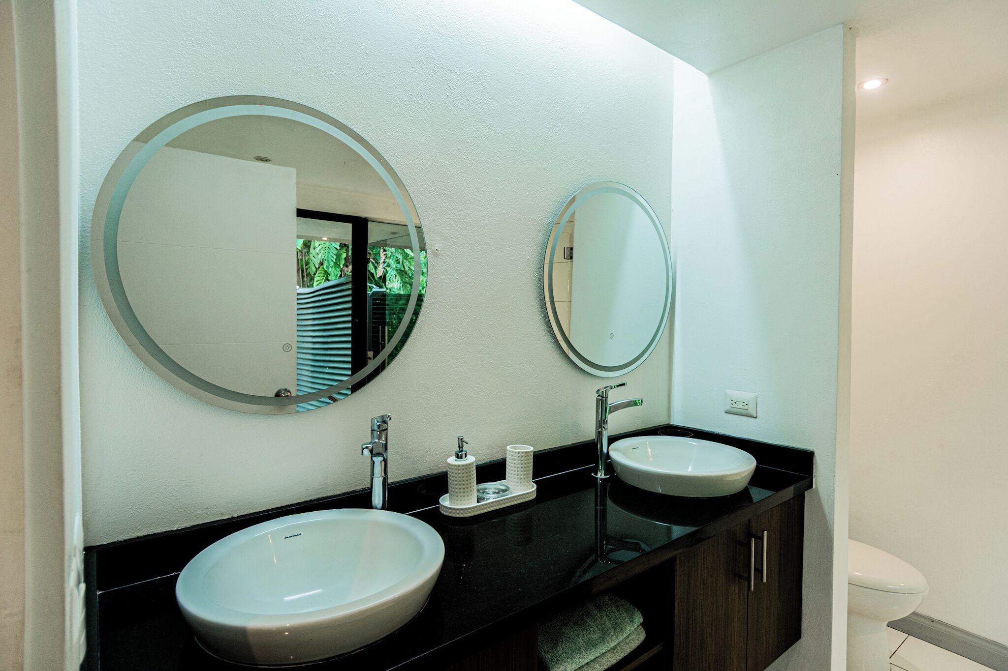 Une salle de bain moderne avec deux lavabos, un grand miroir et des toilettes.