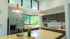 Una cocina moderna con electrodomésticos de acero inoxidable, una isla grande e iluminación colgante.
