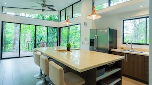 Una cocina moderna con una isla grande, taburetes de bar, un refrigerador y un lavamanos.