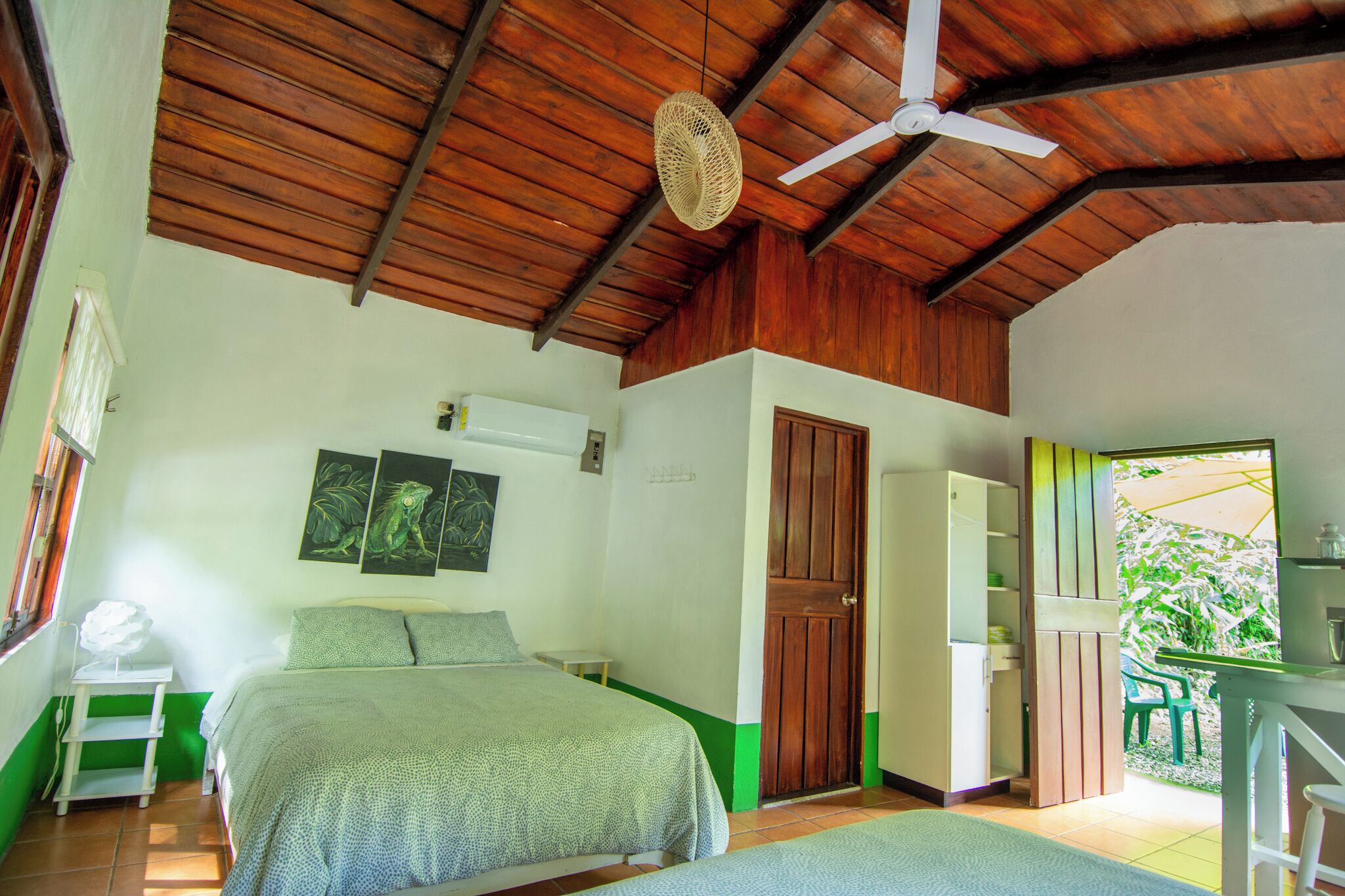 A bedroom with a bed, a ceiling fan, a door, and a view of the outside.