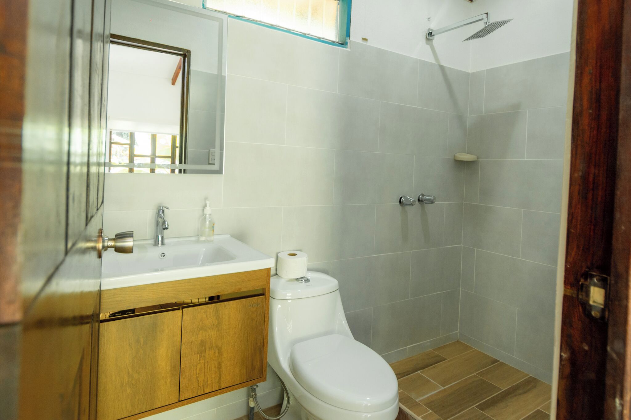 A bathroom with a toilet, sink, mirror, and shower.
