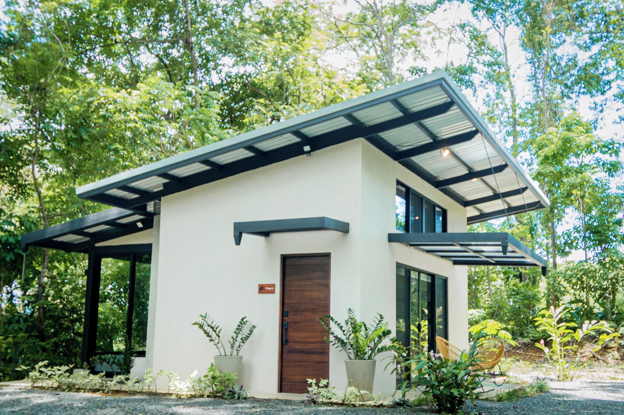 A modern two-story house with a sloped roof, large windows, and a wooden door.