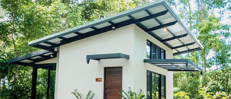 Una casa moderna de dos pisos con techo inclinado, ventanas grandes y puerta de madera.