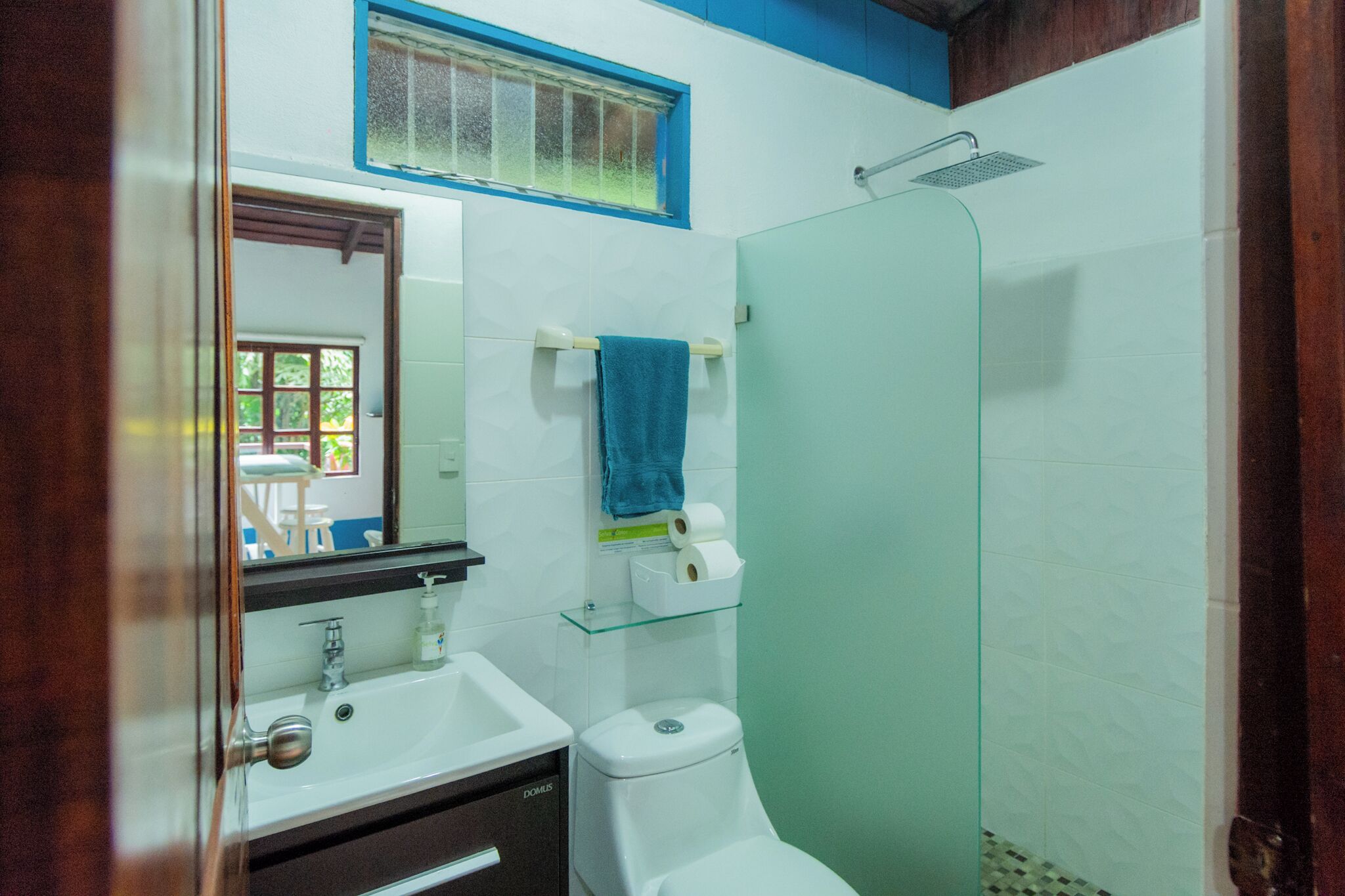 Une salle de bain avec une douche à parois de verre, un lavabo blanc et des toilettes.