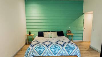 A bedroom with a bed, a nightstand, a small table, and a door.