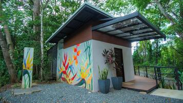 Un bâtiment moderne orné d’une fresque colorée, entouré d’arbres et de plantes en pot.