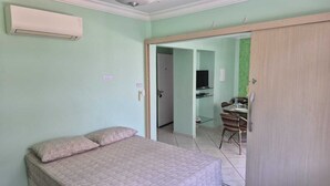 A bedroom with a bed, a desk with a chair, and a wardrobe. - Apartamento Lester Primo Guarujá (Guarujá)