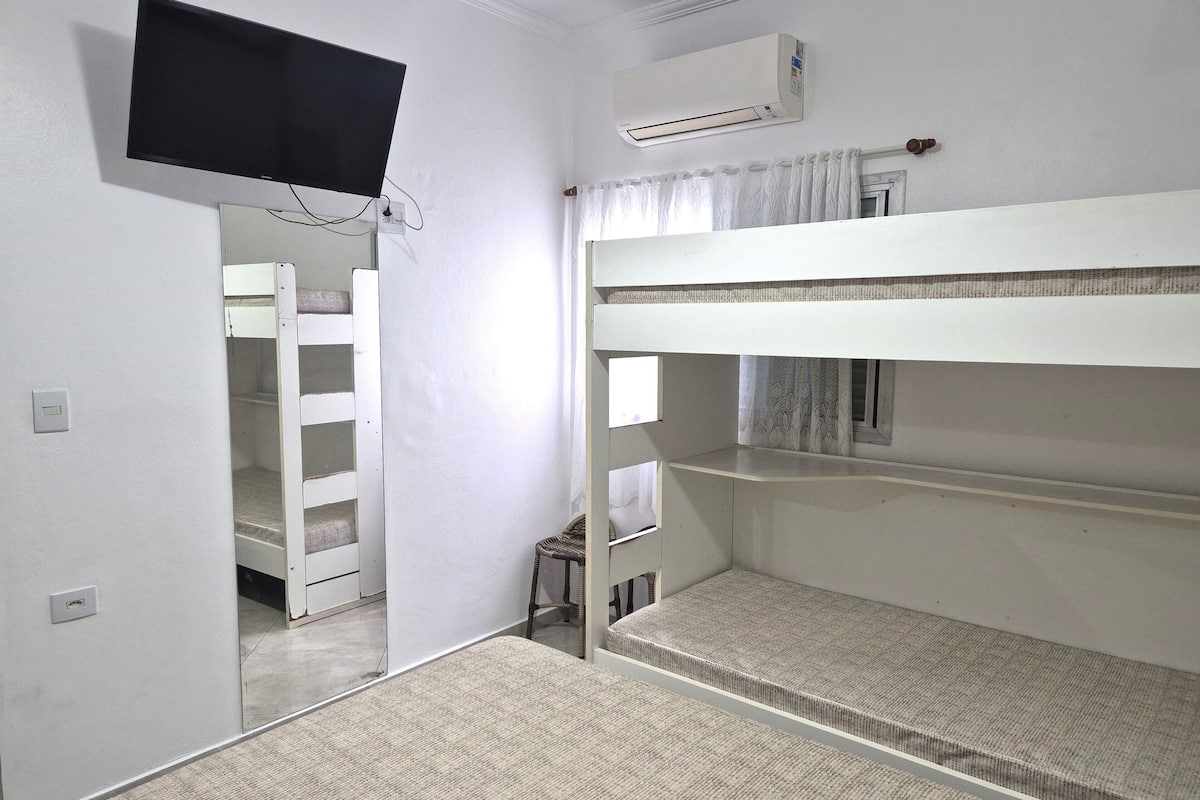A room with bunk beds, a television mounted on the wall, and an air conditioning unit.