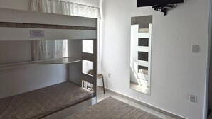 Una habitació amb lliteres, un televisió de pantalla plana penjada a la paret i un mirall.