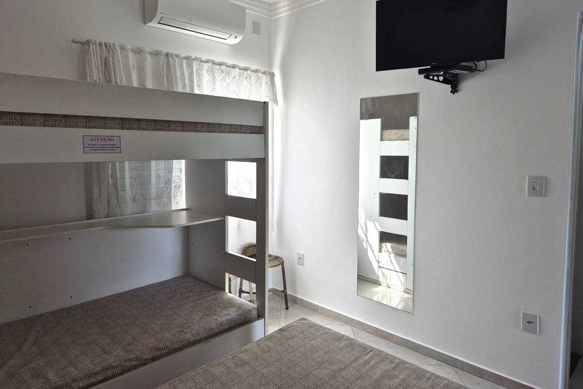 A room with bunk beds, a flat-screen TV mounted on the wall, and a mirror.