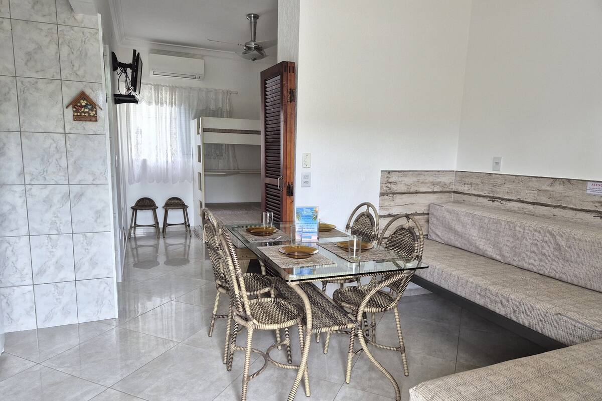 A dining area with a glass table, wicker chairs, a sofa, and a ceiling fan.