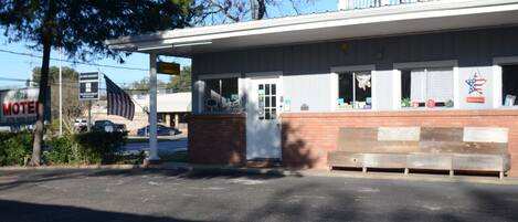 A motel with a covered front area, a brick wall, and a balcony.