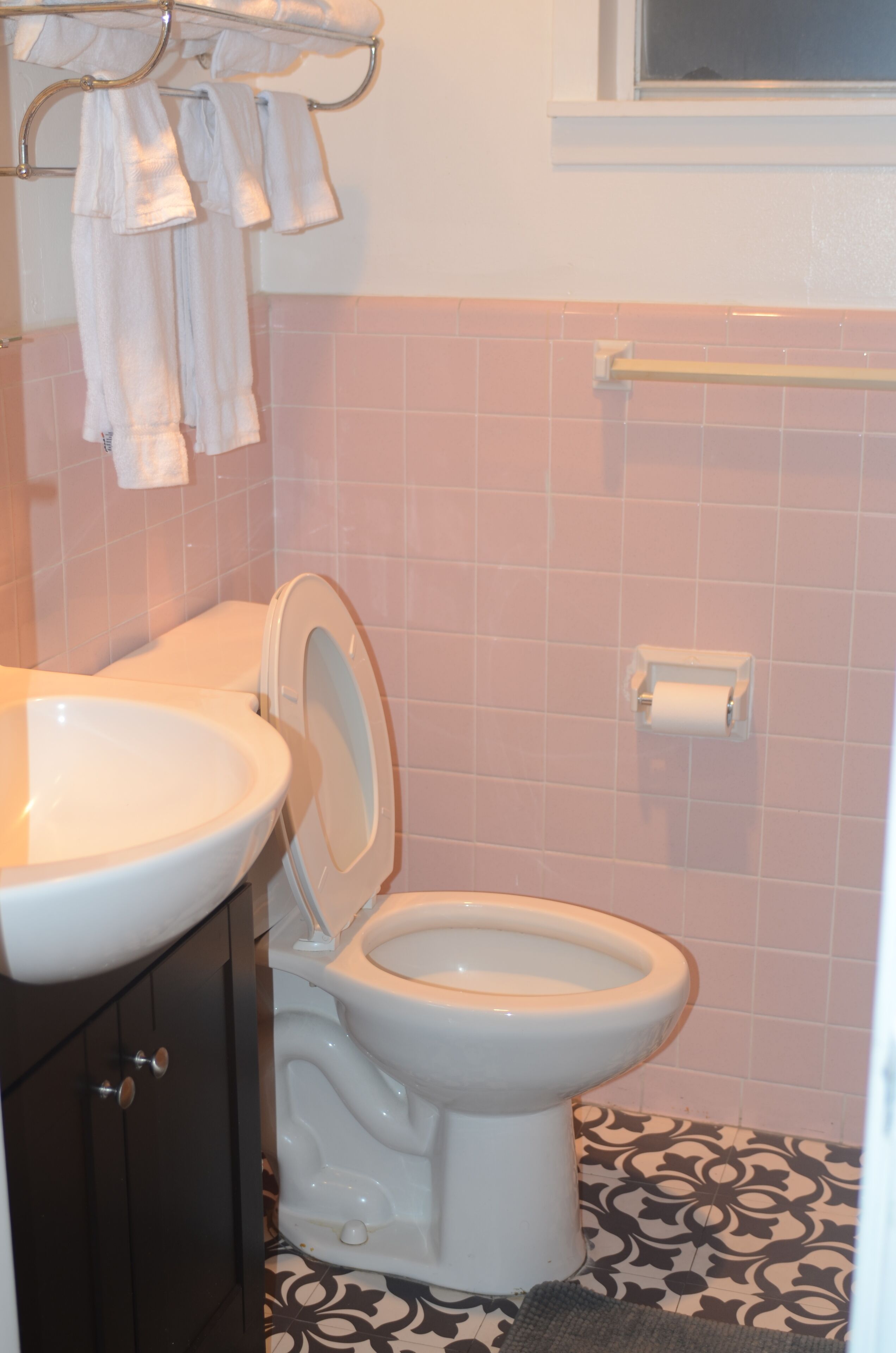 Un bagno con un water bianco, un lavandino e un porta asciugamani.