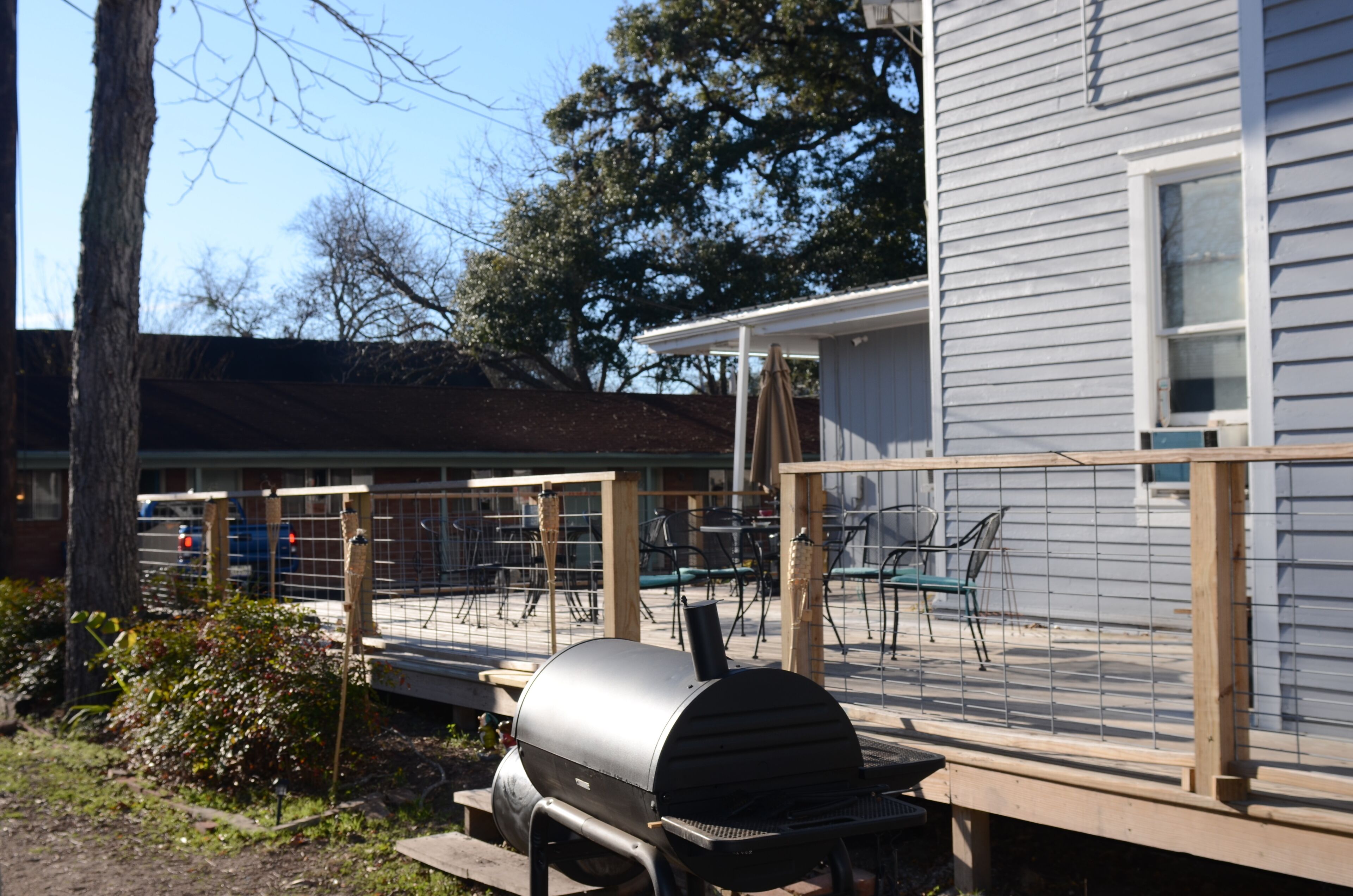 A barbecue grill on a wooden deck with a house in the background.