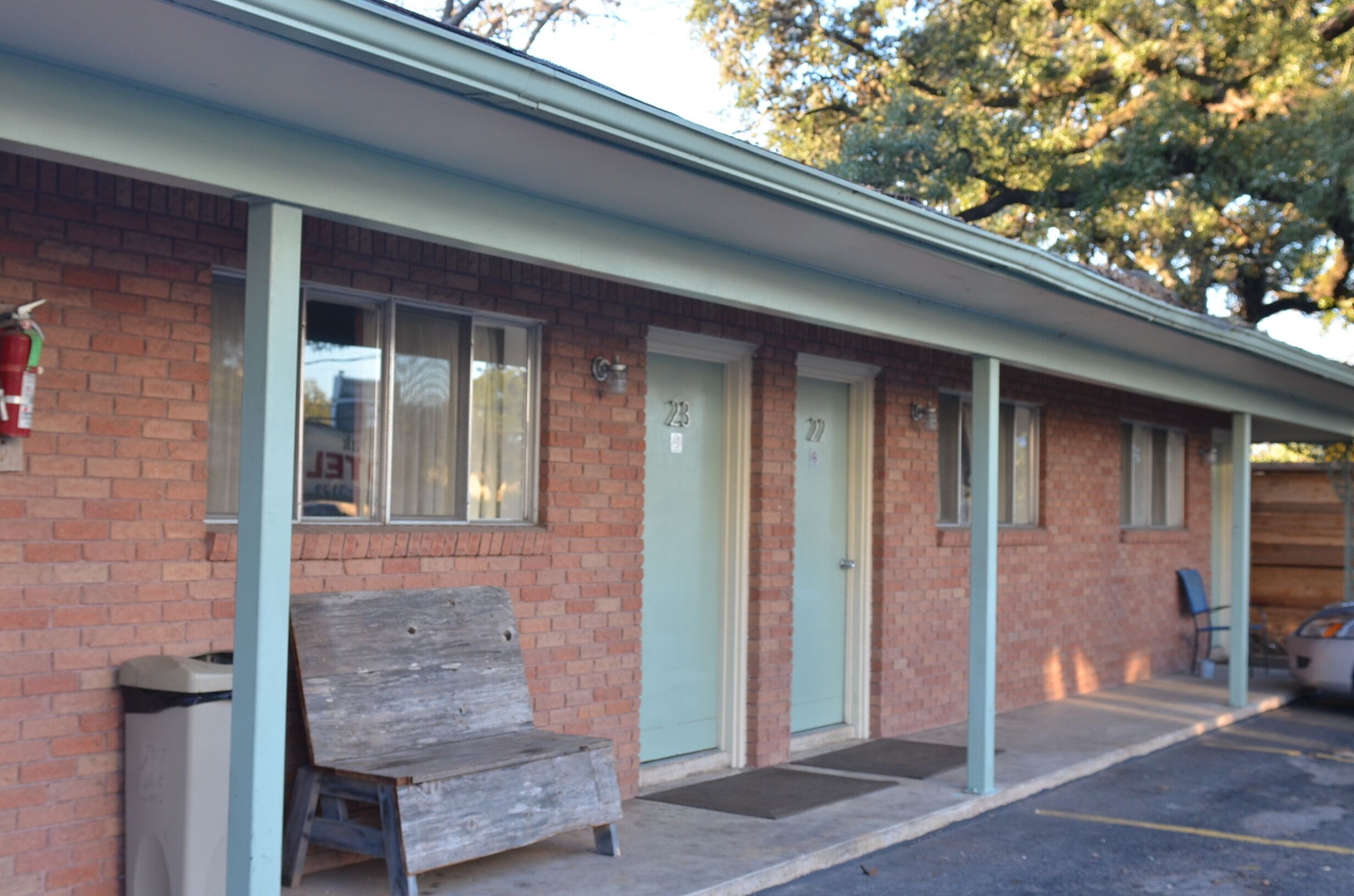 A motel with a brick facade, numbered doors, and a parking area.