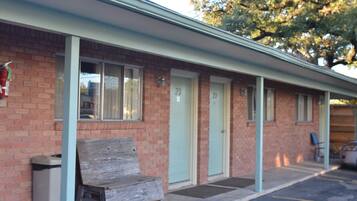 A motel with a brick facade, numbered doors, and a parking area.