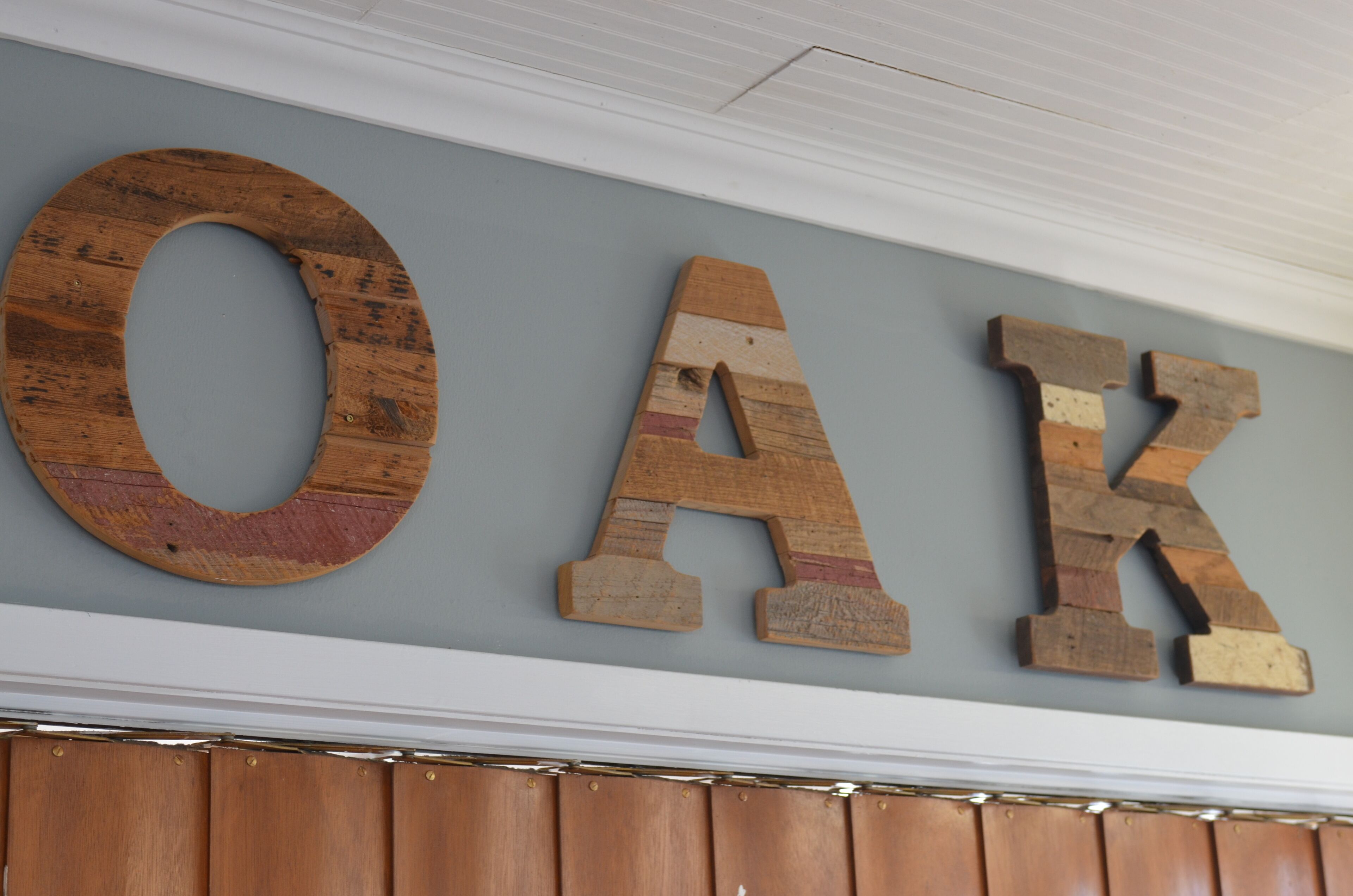 Wooden letters spelling "OAK" on a wall.