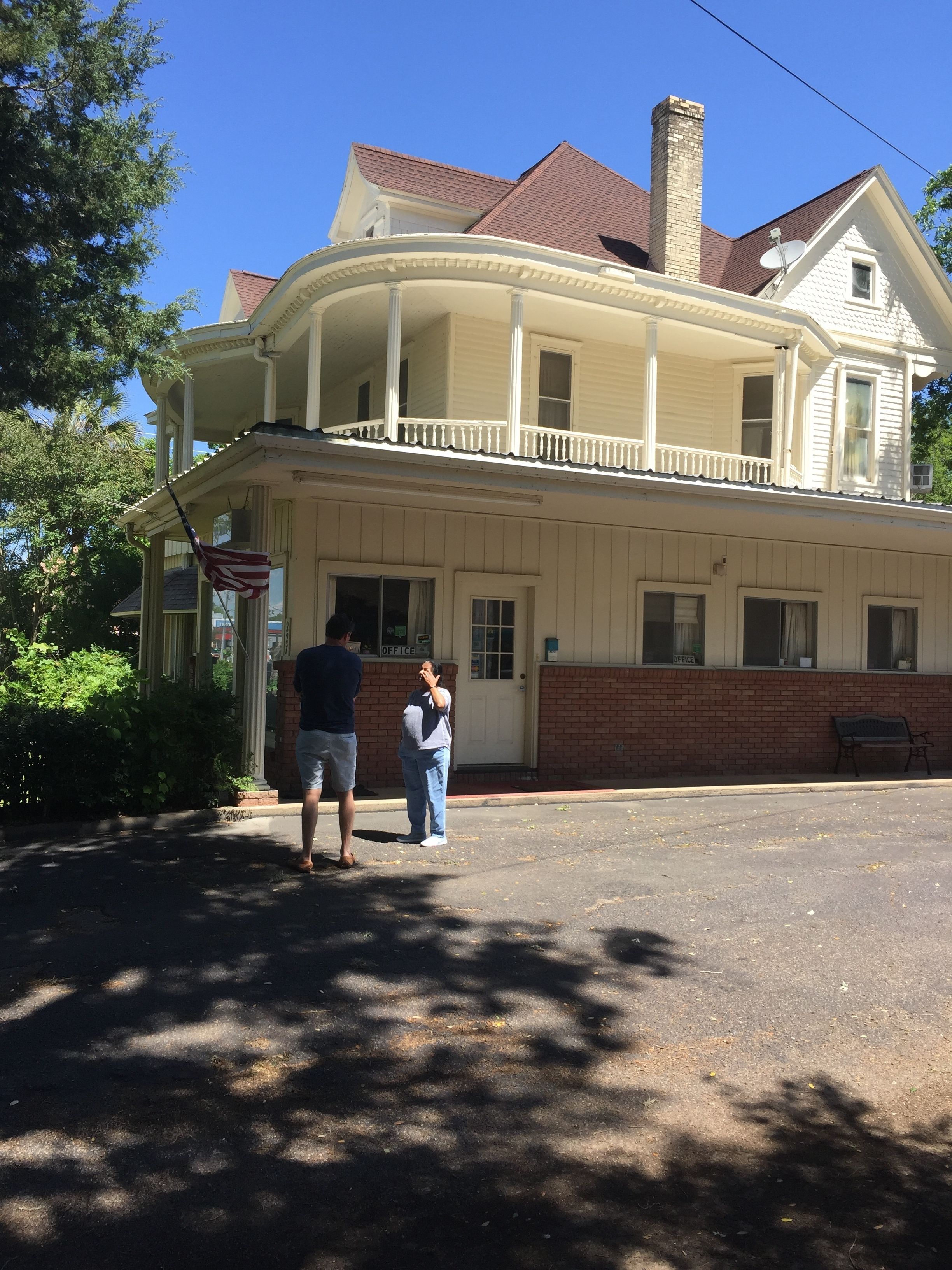 A two-story building with a balcony, a brick foundation, and a chimney.