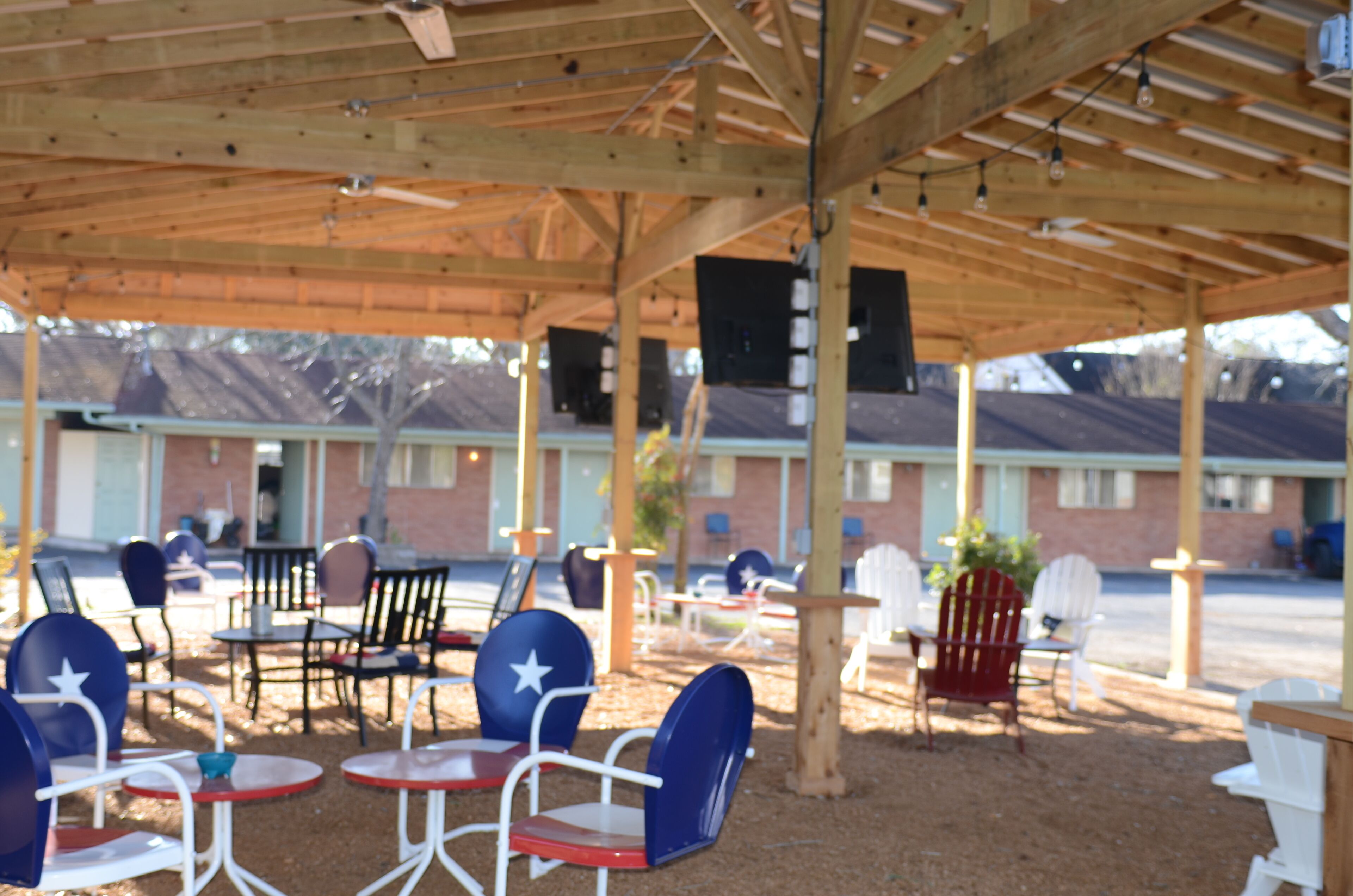 An outdoor seating area with tables and chairs under a wooden pergola.