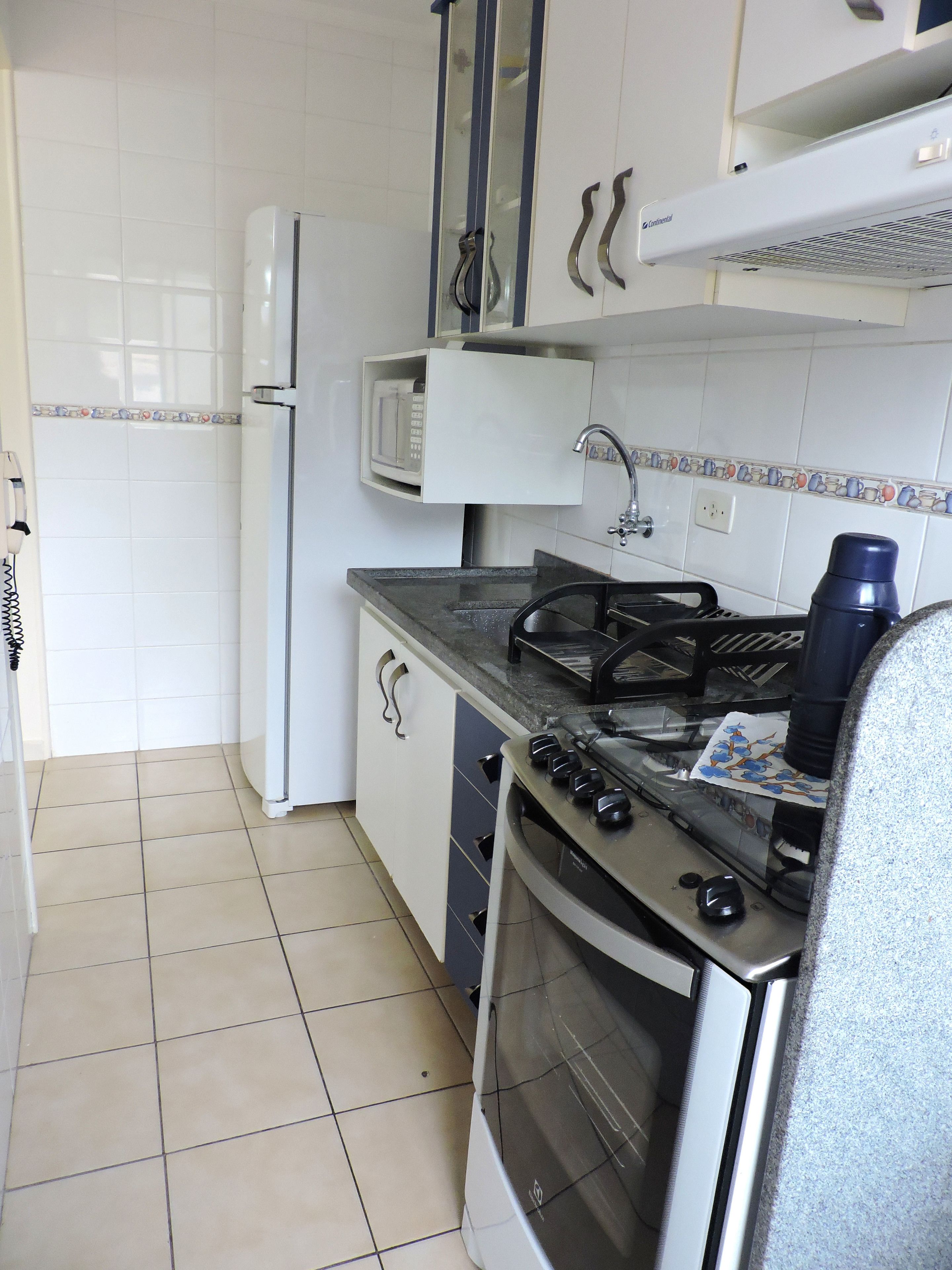 A kitchen with a stove, oven, microwave, and a refrigerator.